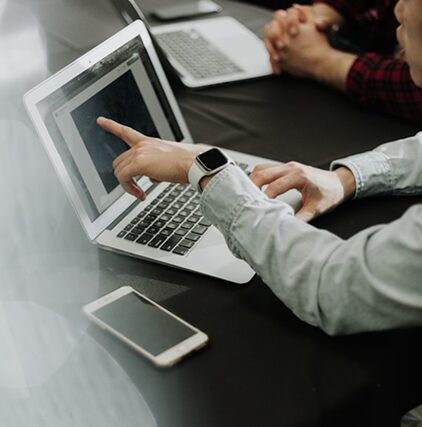 Financial advisor pointing to retirement projections on a laptop screen for a client.