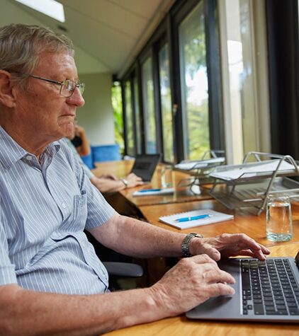 Retired man reviewing his investment portfolio on a laptop in a meeting room