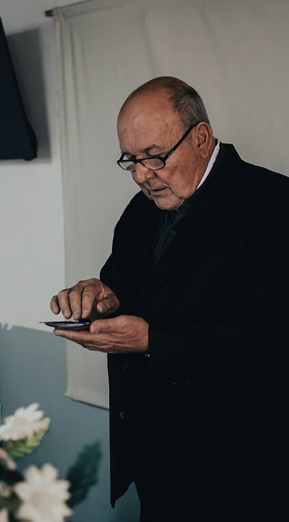 Older man in a dark coat checking his pension account on a tablet