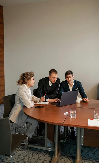 Financial advisor reviewing retirement planning documents with two clients at a conference table